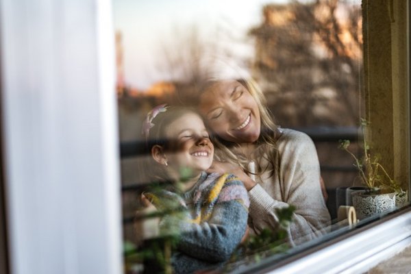 Mutter und Tochter am Fenster genießen ruhige Auszeit