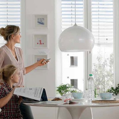 Frau reguliert sommerlichen Wärmeschutz per Fernbedienung